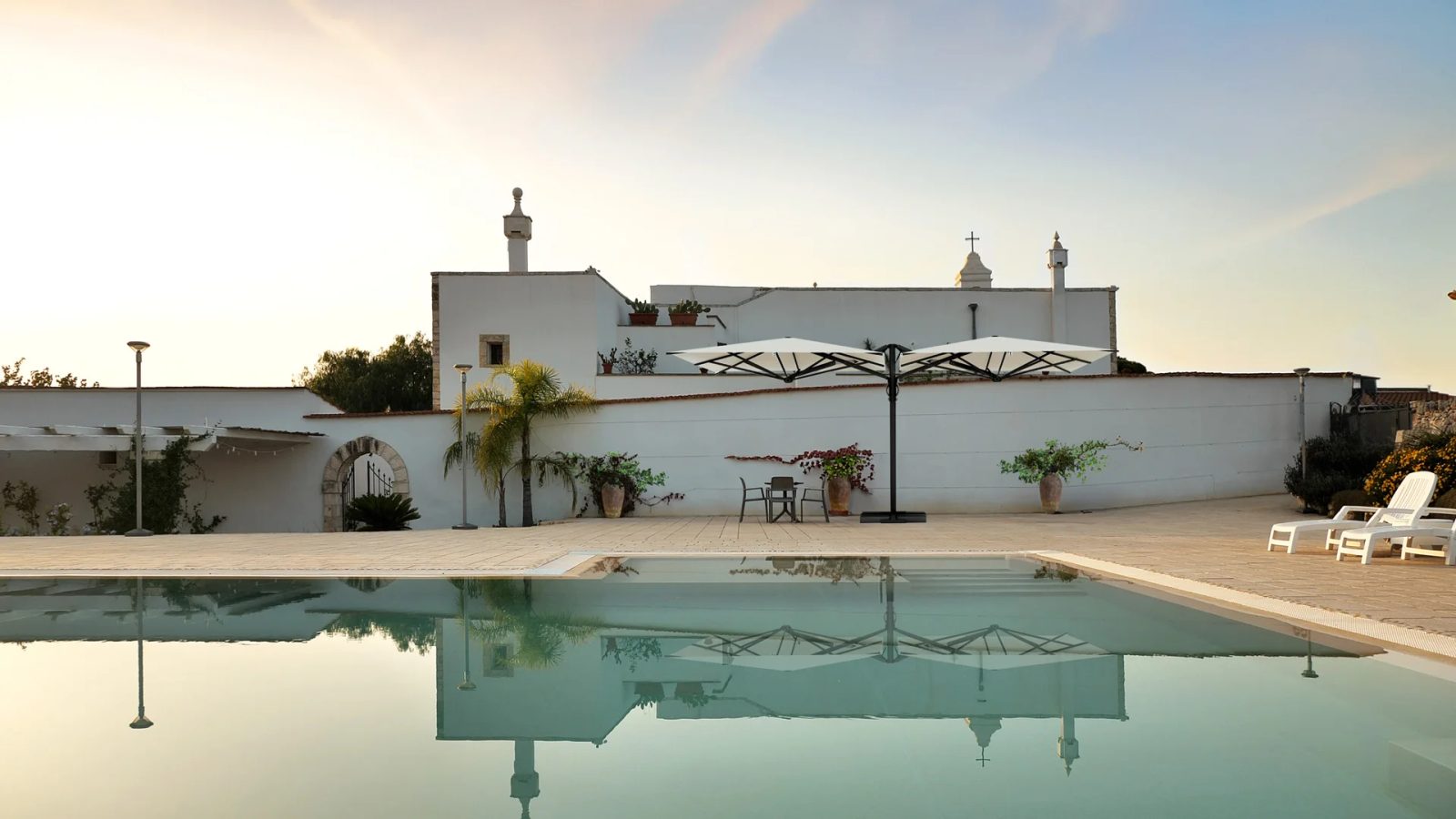 A pool and white masseria at sunset